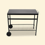 Chariot de plancha en métal noir vu de côté, montrant le plateau supérieur plein, la structure tubulaire, l’étagère inférieure grillagée et les deux roues arrière, présenté sur fond uni clair.