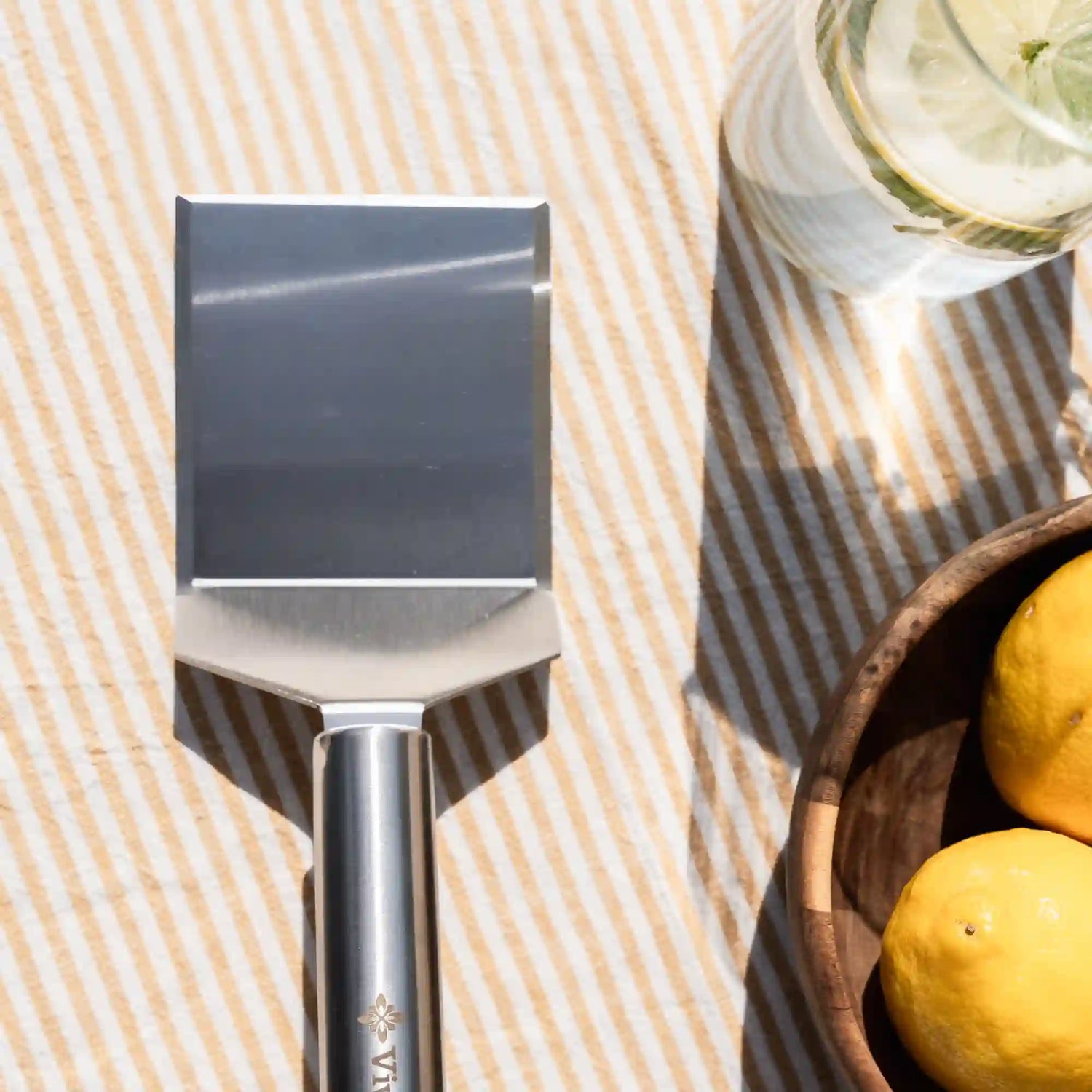Spatule classique Vivaplancha posée près d'un verre et d'un bol de citrons